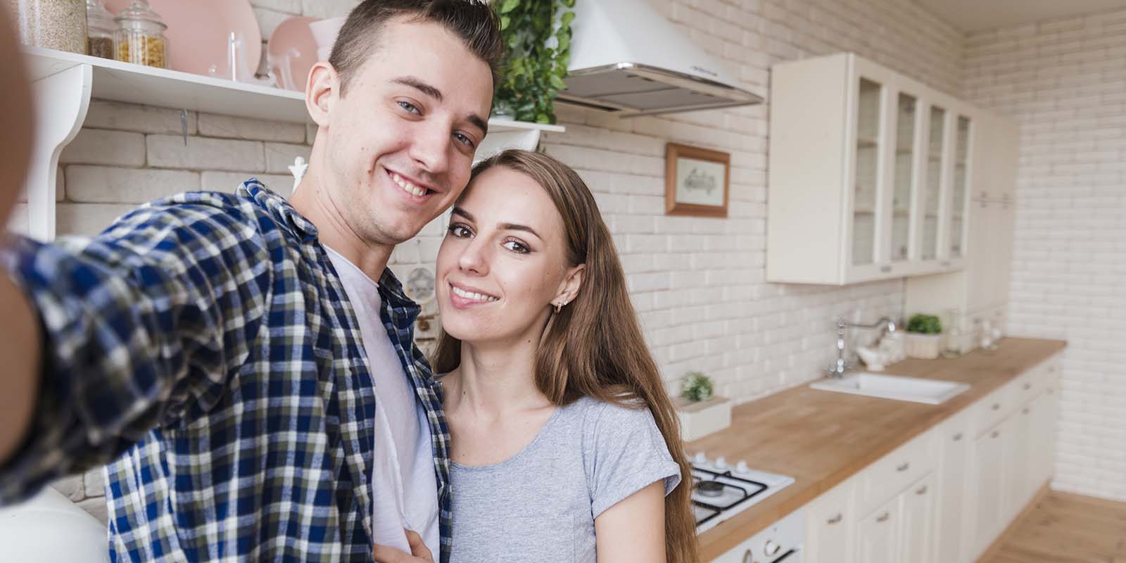 Selfie de pareja joven en cocina con rostros de felicidad de haber alquilado. Gisela Juarez puede ayudarte a realizar la búsqueda y aptitudes para encontrar un buen inquilino.