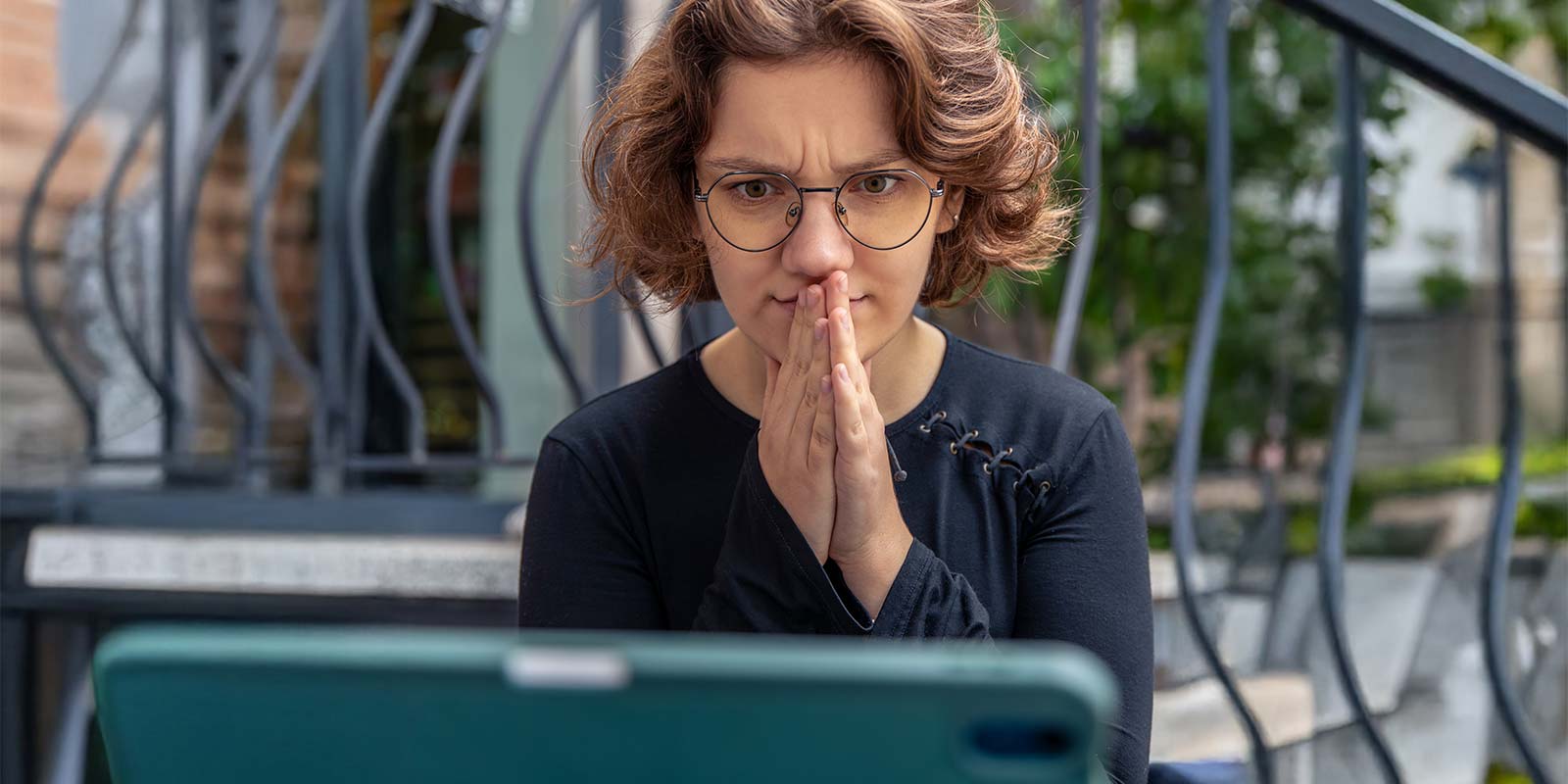 Mujer joven observando su portátil con gesto de sorpresa o preocupación.