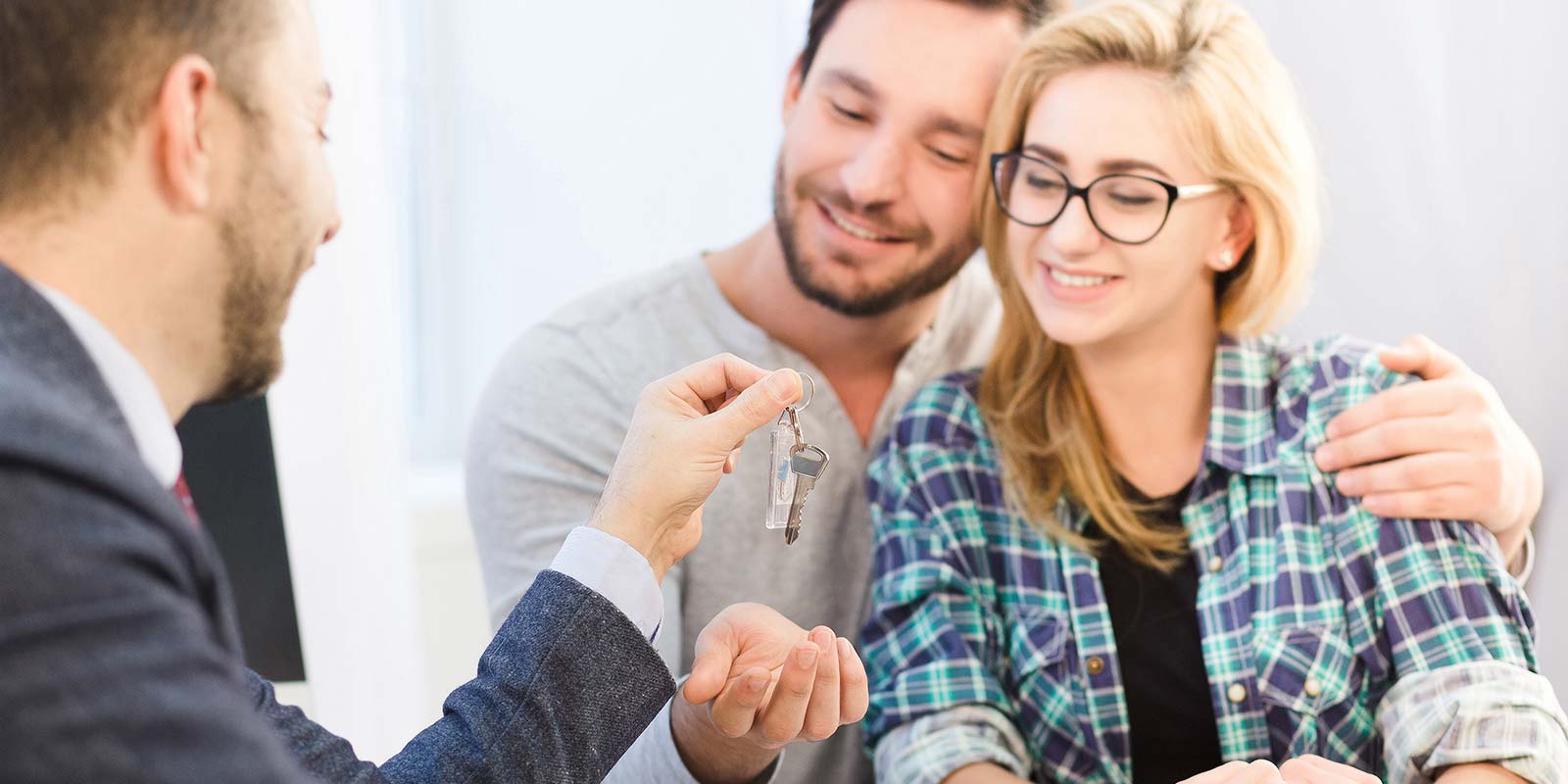 Pareja feliz recibiendo llave de la propiedad que ha adquirido en regla.