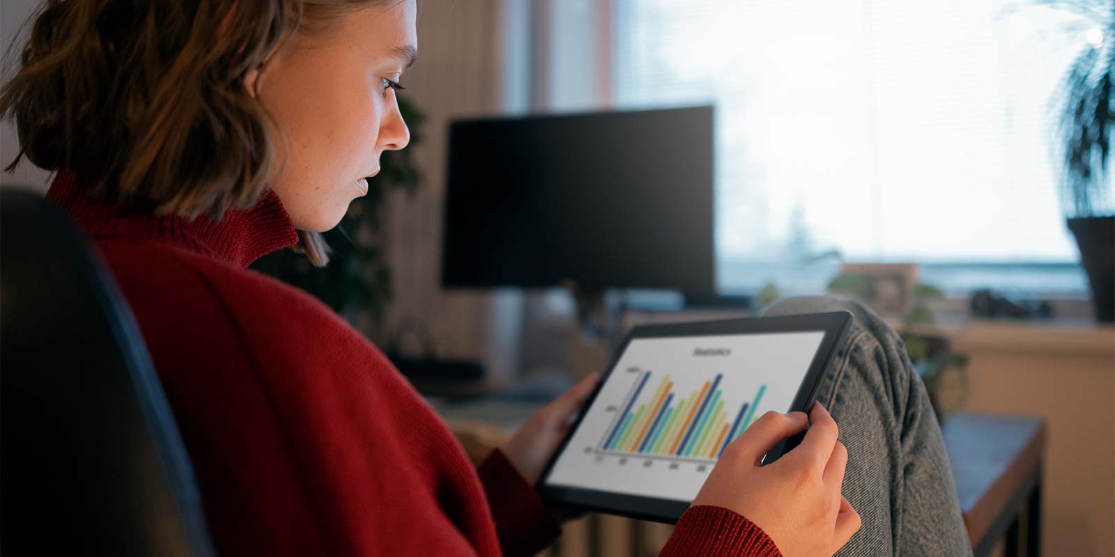 Mujer joven mirando un gráfico de barras en una tablet para poder hacer los cálculos sobre la rentabilidad de su futuro inmueble.