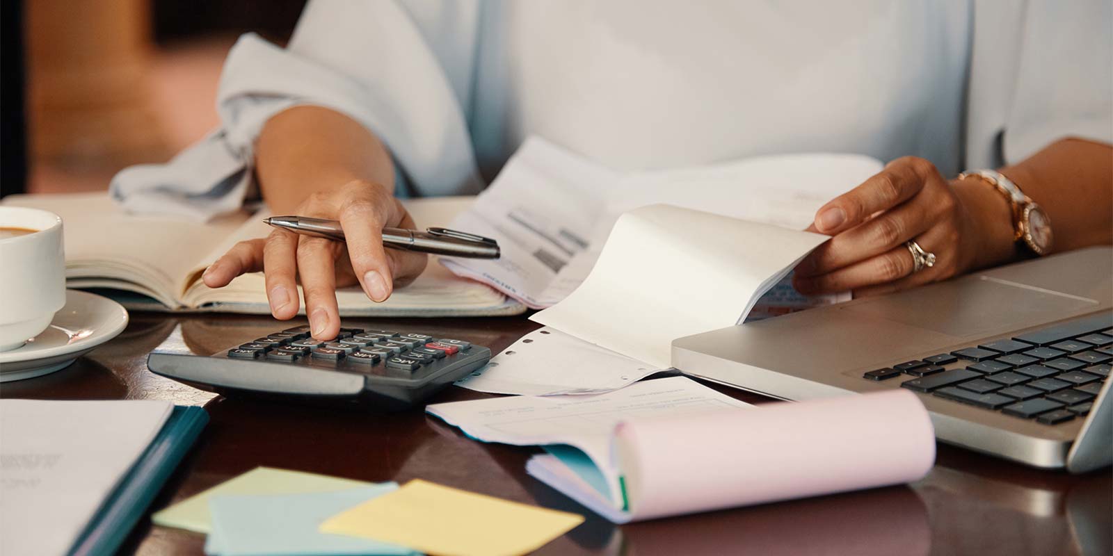 Mujer en escritorio revisando documentación y haciendo cálculos en una calculadora en concepto de revisión de la fiscalización a la hora de vender un inmueble.