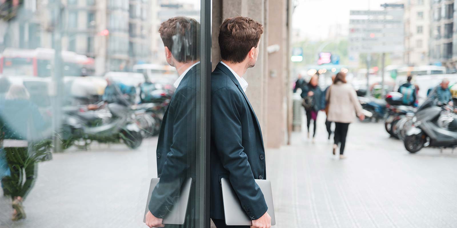 Hombre joven emprendedor, de perfil y espalda a la cámara, reflejado en el vidrio de un comercio. En concepto de la decisión de elegir a un profesional (o no) a la hora de vender tu inmueble. Gisela te dará tips para que tu elijas lo que creas conveniente para tí.