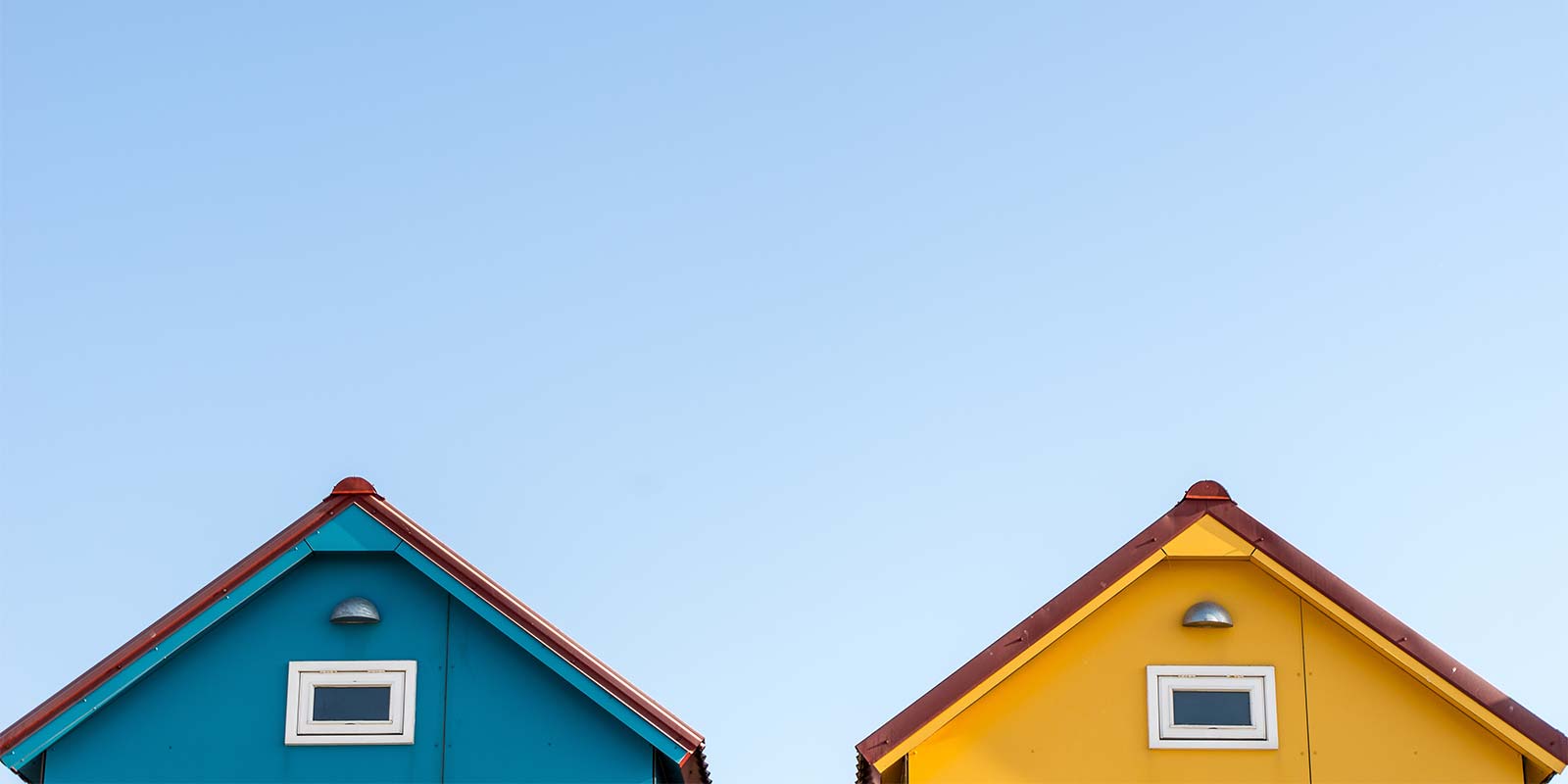 Imagen de la parte superior de dos casas de distintos colores. En concepto de comprar una segunda casa como opción de vacacional y/o inversión.