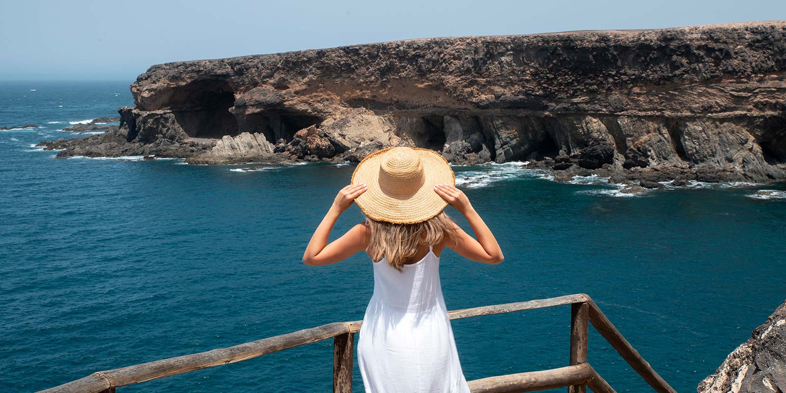 Mujer con sombrero en un mirador frente al mar. En referencia de la opción por la que el turista invierte en un inmueble en la Costa del Sol, turismo o vivienda.