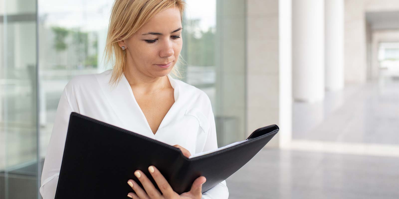 Imagen de una mujer joven revisando documentación. En referencia a realizar un seguimiento luego de la operación inmobiliaria para informar los pasos siguientes, conocer la situación y generar confianza.